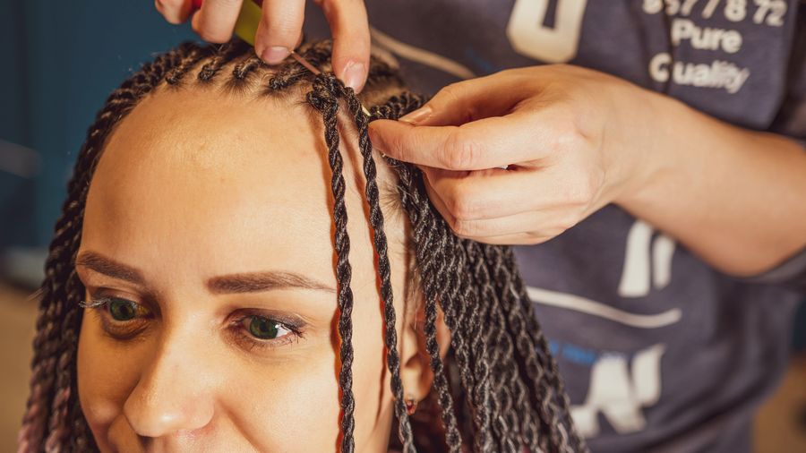Braider's hands adding long twists to a client's hair, close up