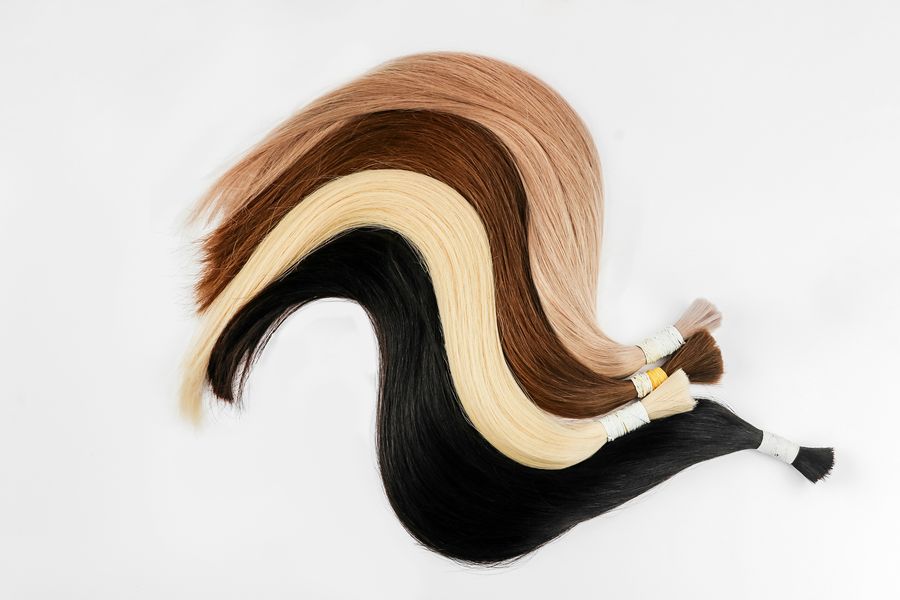 Rolled hair extension wefts in black, brown, honey and platinum blonde on a white background
